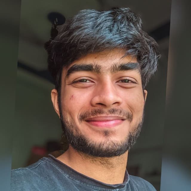 Portrait of Aditya, smiling, photographed in daylight.